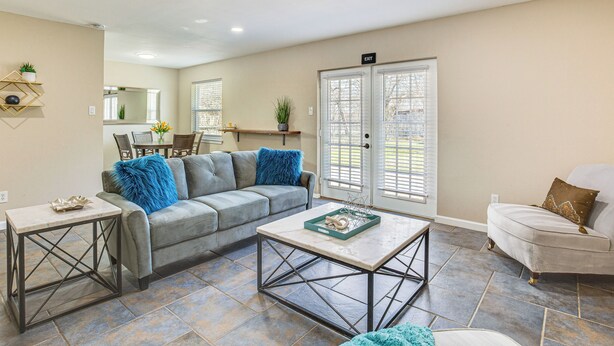 A living room with a grey sofa, a white armchair, a coffee table, and a dining area in the background. - 5 Mi to Fort Worth Stockyards: Home w/ Yard! (Haltom City)