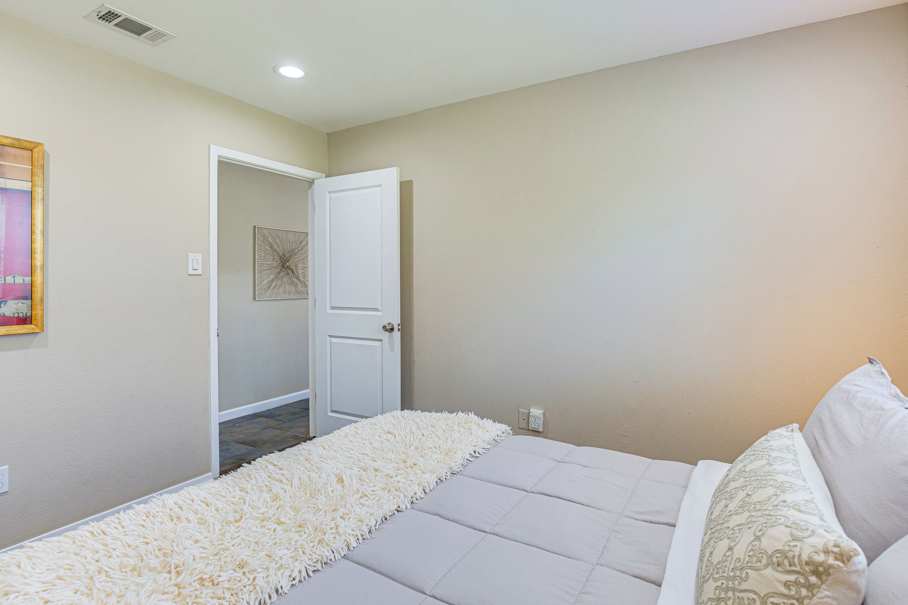 Une chambre à coucher avec un lit, une porte blanche et un tapis blanc à motifs.