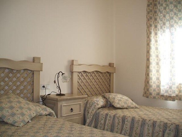Une chambre avec deux lits, une table de chevet et une lampe.