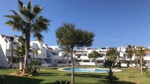 A resort with multiple white buildings, a swimming pool, and palm trees. - Ideal for family trips, close to Rocio and Portugal, pets welcome. (Islantilla)