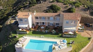 Un edificio de varios pisos con piscina, mobiliario exterior y jardín ajardinado.