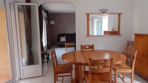 Un comedor con una mesa y sillas de madera, un espejo en la pared, y vista a otra habitación.
