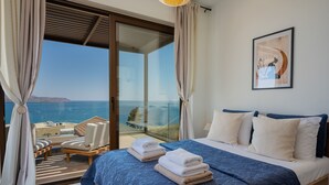 Ein Schlafzimmer mit Bett, Meerblick und Balkon mit Sitzgelegenheit.