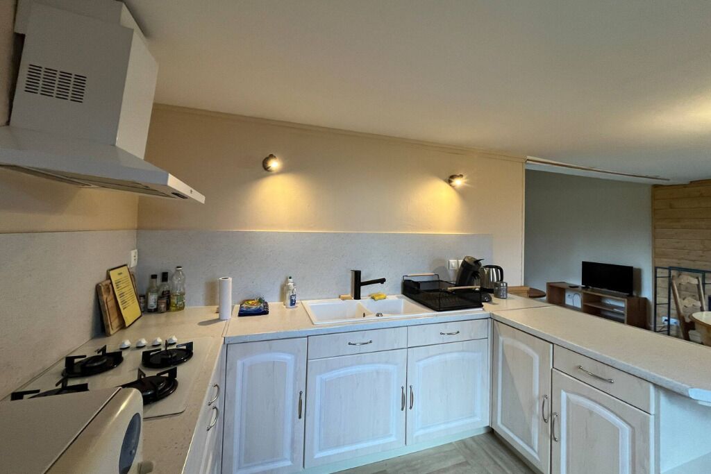 Una cocina moderna con armarios blancos, una estufa a gas, un fregadero y una cafetera.