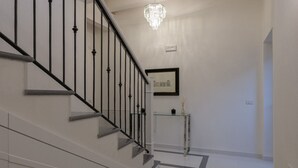 A staircase with black railings, a chandelier, and a framed picture on the wall. - Liberty Suite - One Bedroom Apartment, Sleeps 2 (Piovene Rocchette)