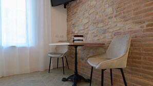 A room with a stone wall, a table with a book, and two chairs. - Liberty Suite - One Bedroom Apartment, Sleeps 2 (Piovene Rocchette)