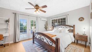 A bedroom with a wooden bed, a ceiling fan, a nightstand, and a view through the glass doors. - Game room & Fire Pit, Close to Downtown! (Paso Robles)