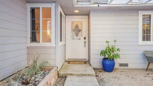 A house with a white exterior, a front door with a decorative glass panel, a welcome mat, a potted plant, and a chair. - Game room & Fire Pit, Close to Downtown! (Paso Robles)