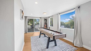 A room with a pool table, a bookshelf, and large windows. - Game room & Fire Pit, Close to Downtown! (Paso Robles)