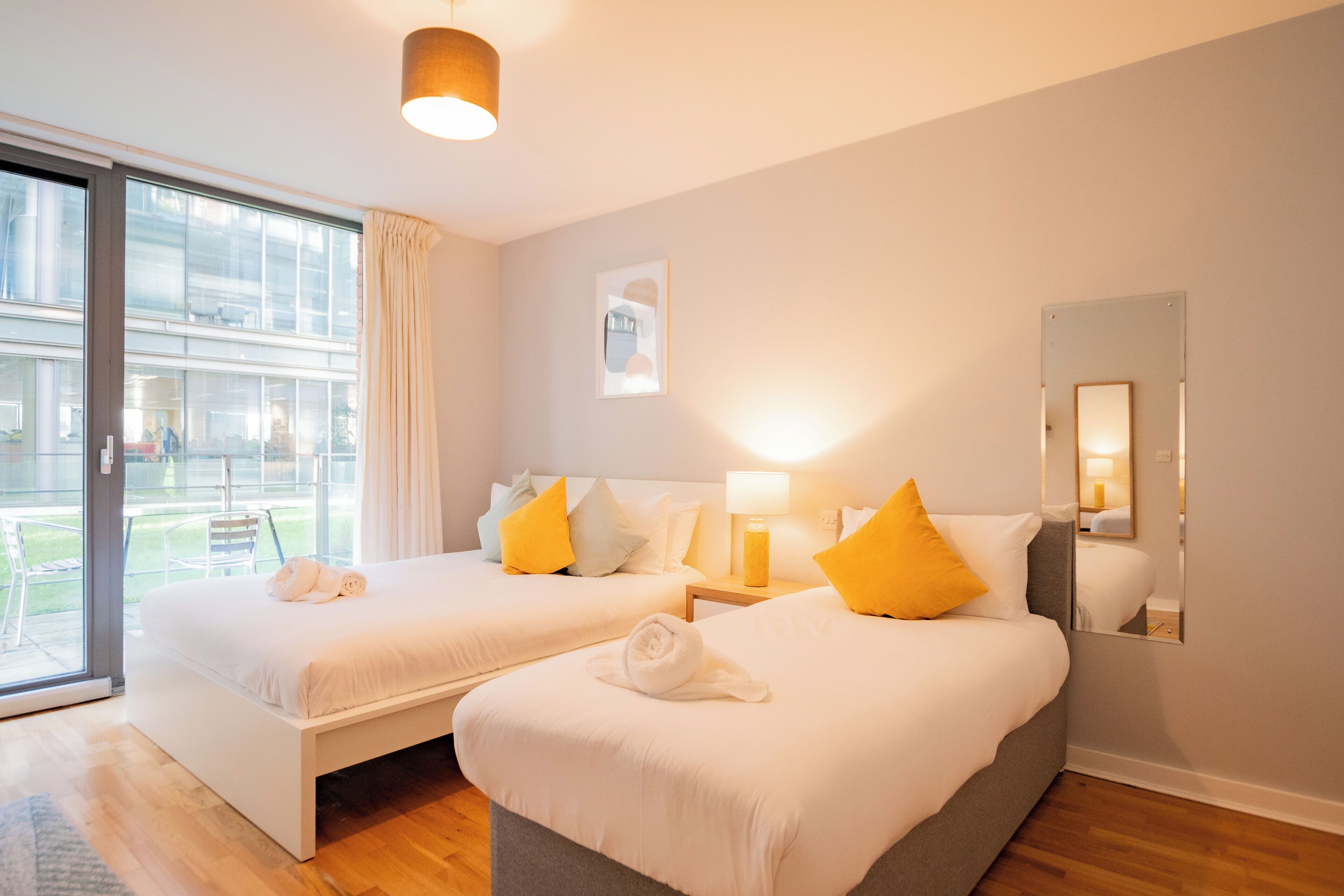 A hotel room with two beds, a large window, and a sliding door to an outdoor area.