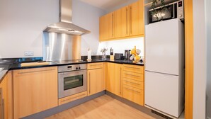 Eine moderne Küche mit Holzschränken, Edelstahlgeräten und einer eingebauten Mikrowelle.