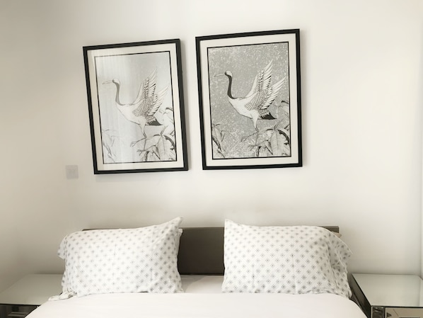 A bedroom with a bed, two framed wall art pieces of birds, and patterned pillows. - Splendid Apartments at Embassy Gardens (Accra)
