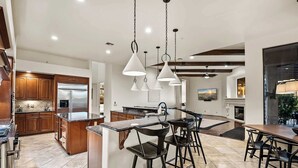 A spacious kitchen with a central island, wooden cabinets, and a stainless steel refrigerator. - Private Movie Theater, Luxury Pool, Hot Tub (Scottsdale)