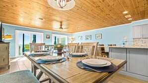 A dining area with a wooden table set for four, a chandelier, and a view of the outside.