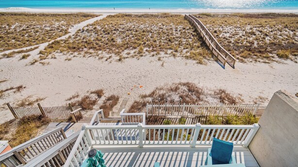 A beach view with a wooden deck and a white fence.