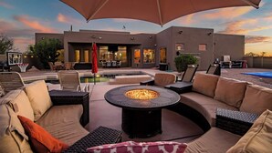 An outdoor patio area with a fire pit, lounge chairs, and a pool. - 5BR, Pool, Patio, Outdoor TV & In-Pool Hoops (Scottsdale)