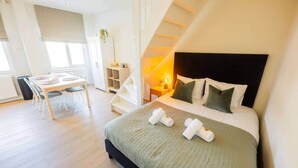 Una habitación de hotel moderna con una cama grande, un escritorio y una escalera.