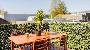 Una mesa con sillas y una planta en maceta en una terraza en la azotea.