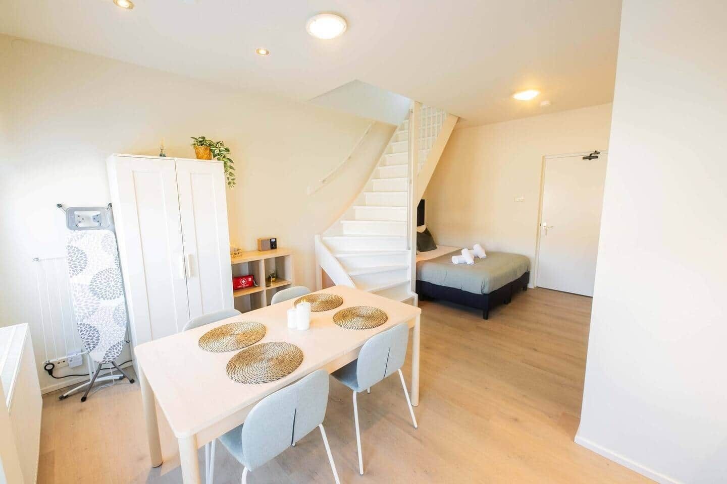 A compact living space with a dining area, a staircase, and a small seating area.