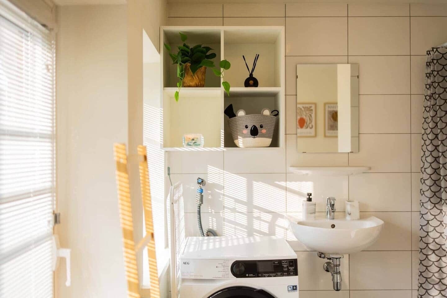 Ein modernes Badezimmer mit Waschmaschine, Waschbecken und einem Spiegel darüber.