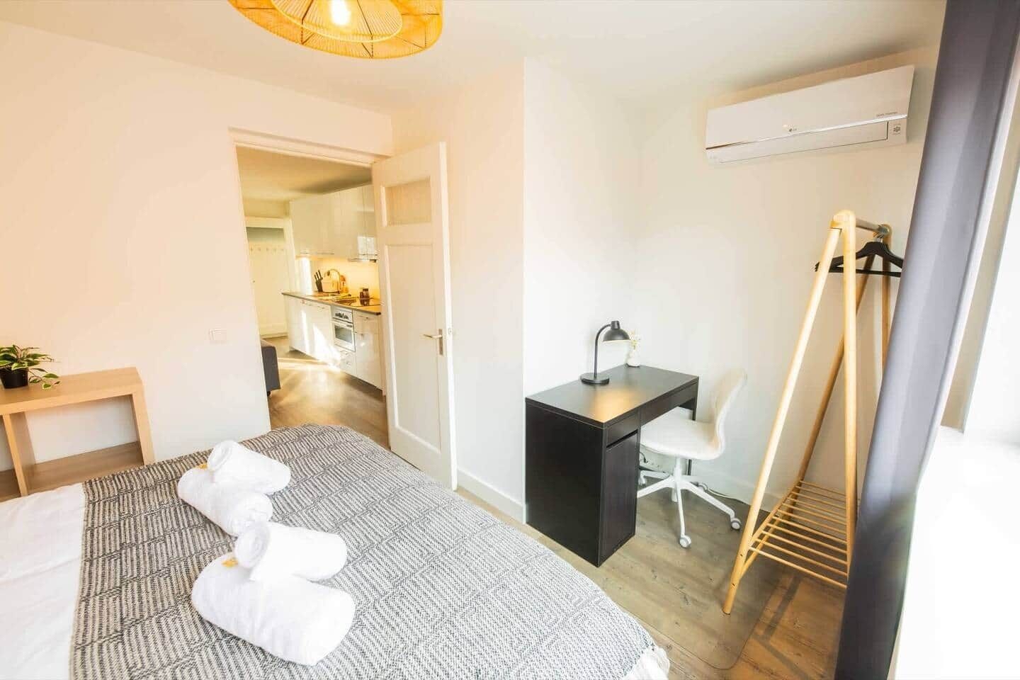 Una habitación de hotel con una cama, un escritorio, una silla, una mesita y un armario.