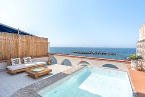 Eine Dachterrasse mit Pool, Sitzgelegenheit und Blick aufs Meer.