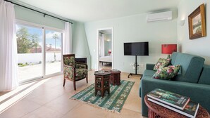 Ein Wohnzimmer mit einer Couch, einem Sessel, einem Fernseher und einem Bücherregal.