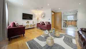 A modern living room with a sofa, a TV, a lamp, and a rug.