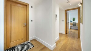 A hallway with wooden doors, white walls, and a wooden floor.