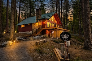 A lodge with a stone chimney, wooden exterior, and a porch with railings. - Riverhouse 3 Bedroom Home (Leavenworth)