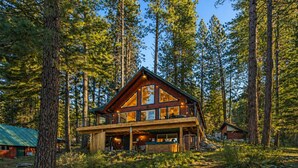 Eine zweistöckige Holzhütte mit Balkon, umgeben von hohen Kiefern.