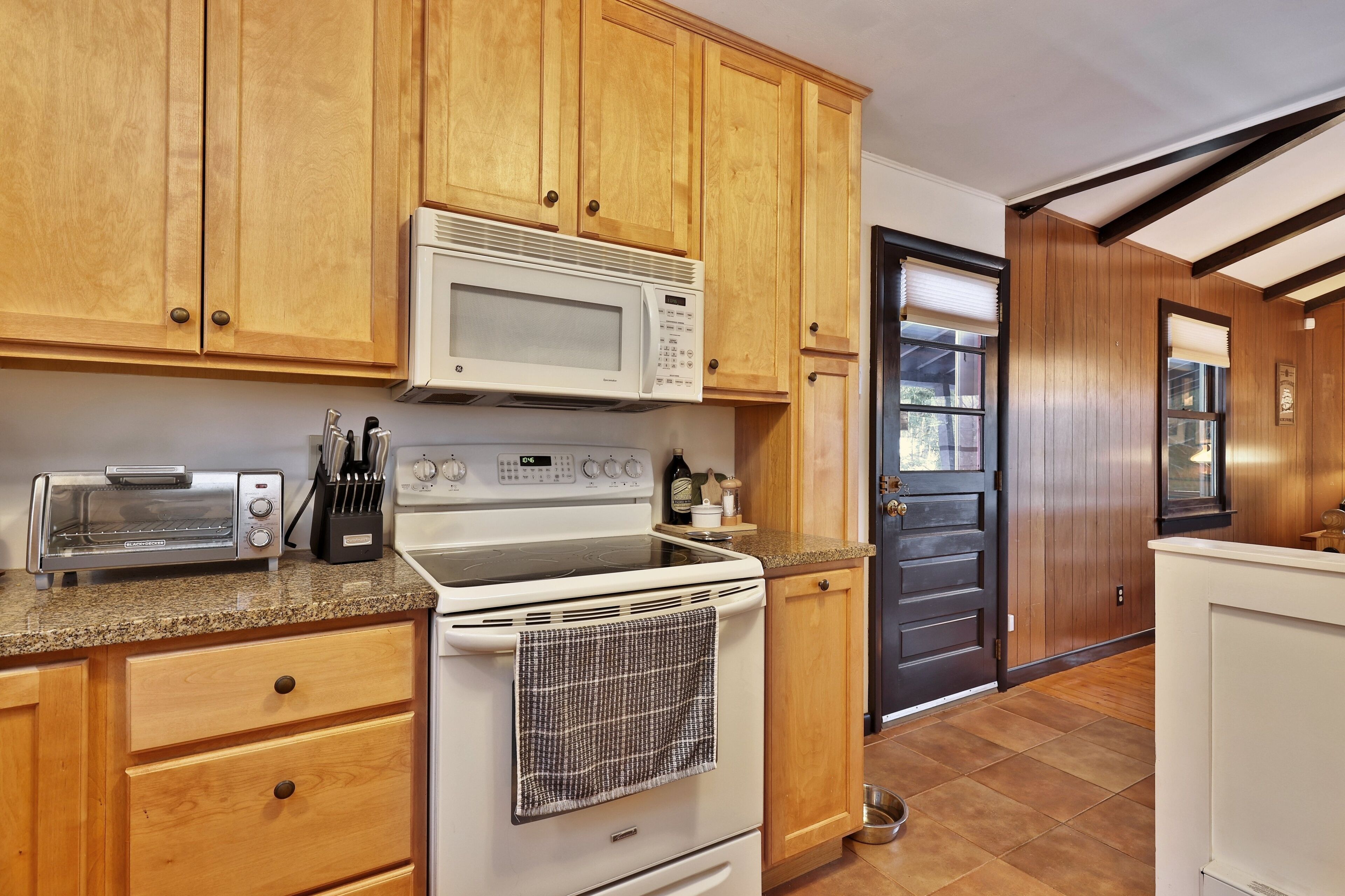 A kitchen with wooden cabinets, a microwave, a toaster, and a stove.
