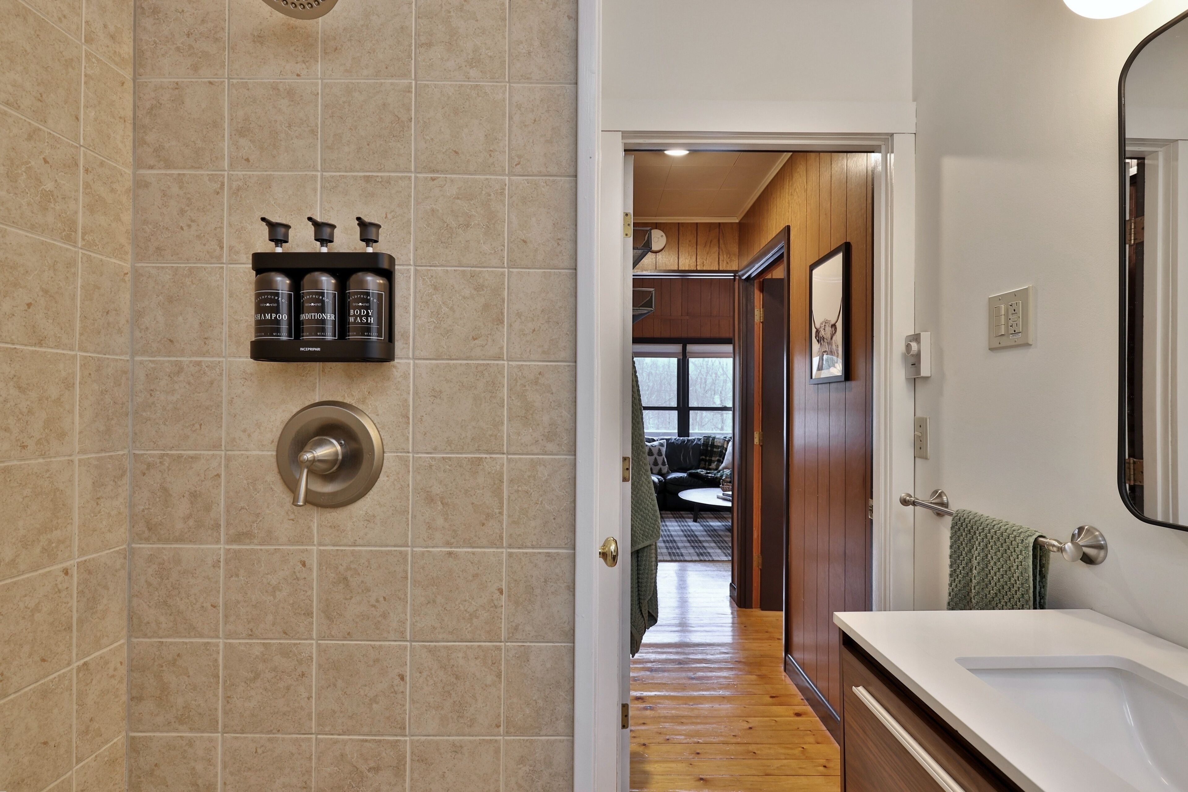 A bathroom with a shower, a sink, and a toilet. There are toiletries on a shelf.