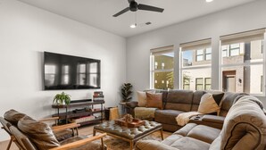 A modern living room with a large flat-screen TV, leather sofas, and a ceiling fan. - Villa #24 At Bloomington Country Club 4 Bedroom Townhouse (St. George)