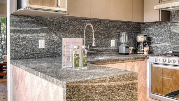 A kitchen with a granite countertop, a built-in microwave, a coffee maker, and a stove.