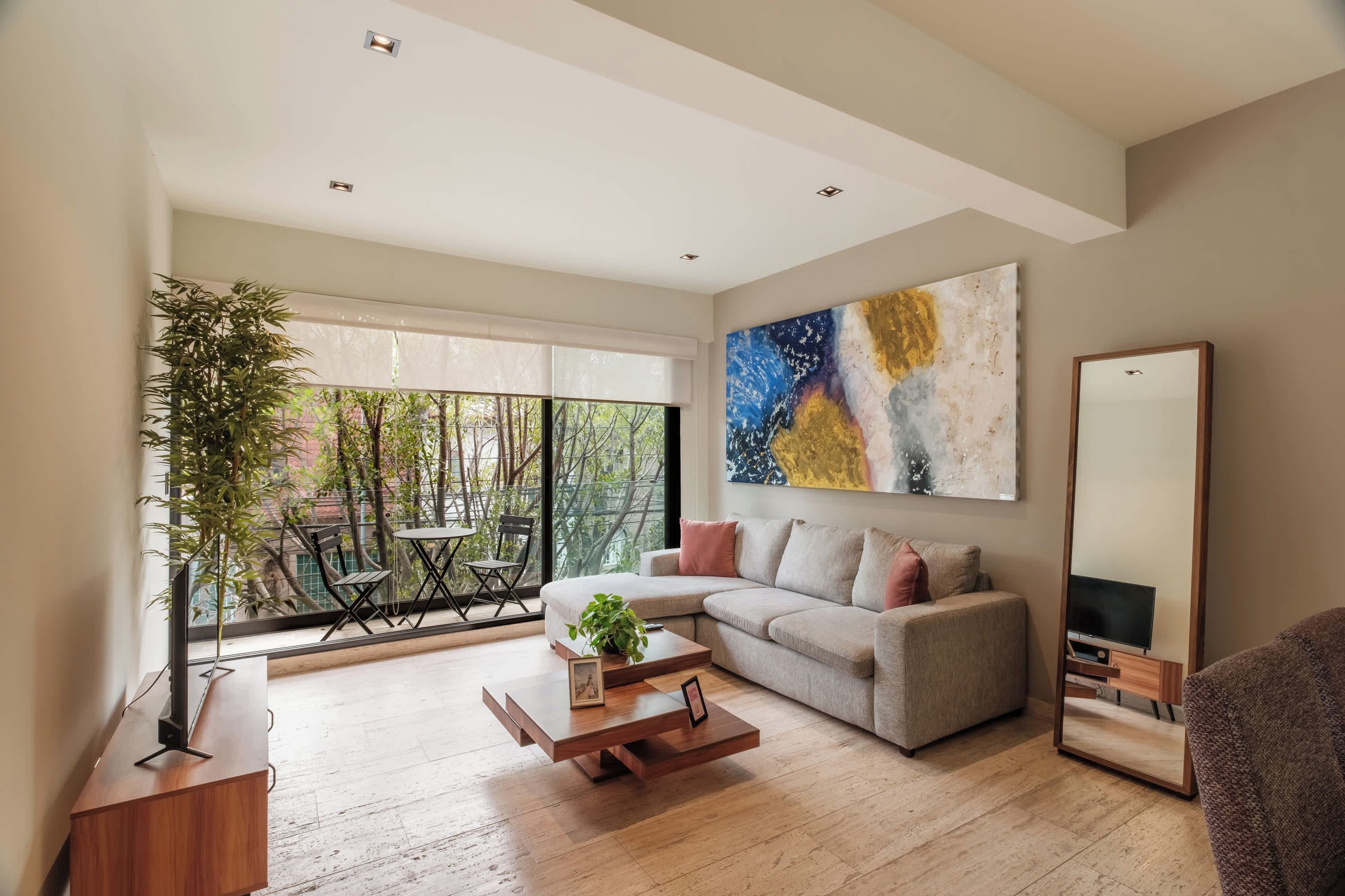 A modern living room with a sofa, coffee table, and a large abstract painting.