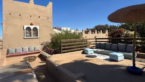 A rooftop terrace with outdoor seating, a decorative wall, and a clear blue sky. - LES ETOILES DU KSAR (Mirleft)