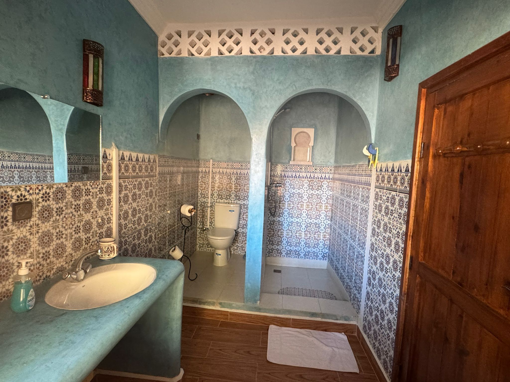 A bathroom with a sink, mirror, and arched alcoves.
