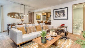 A modern living room with a sofa, coffee table, and a dining area with chairs and a table. - Chic 2BR in Condesa  Rooftop Pool Fast WiFi (Ciudad de México)