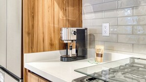A modern kitchen with a coffee machine, a glass countertop, and a wooden cabinet. - Chic 2BR in Condesa  Rooftop Pool Fast WiFi (Ciudad de México)