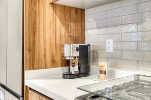 Une cuisine moderne équipée d’une machine à café, d’un plan de travail en verre et d’un meuble en bois.