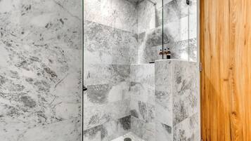 A shower with marble tiles and a wooden door.