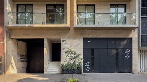 A multi-story building with a ground-level entrance, a small tree, and a number '21' on the wall. - Chic 2BR in Condesa  Rooftop Pool Fast WiFi (Ciudad de México)