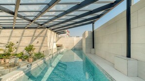 A swimming pool with a glass ceiling, surrounded by tiled walls and potted plants. - Chic 2BR in Condesa  Rooftop Pool Fast WiFi (Ciudad de México)