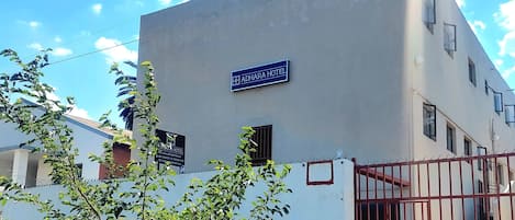A building with a sign reading "ADHARA HOTEL" and a gated entrance.