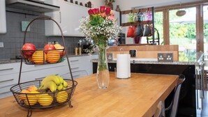 Un comptoir de cuisine avec un panier de fruits, un vase de fleurs et une machine à café.