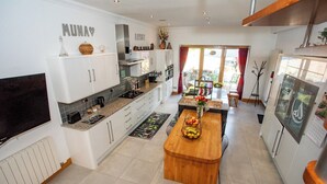Une cuisine moderne avec des meubles blancs, un îlot central en bois et une vue sur l’extérieur.