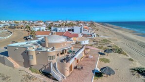 En fastighet vid kusten med en uteplats, en swimmingpool och utsikt över stranden och havet.