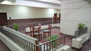 A hotel lobby with a seating area, a staircase, and potted plants. - Sri Sai Residence (Tumkur)