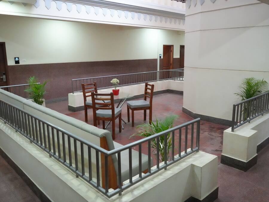 A hotel lobby with a seating area, a staircase, and potted plants.